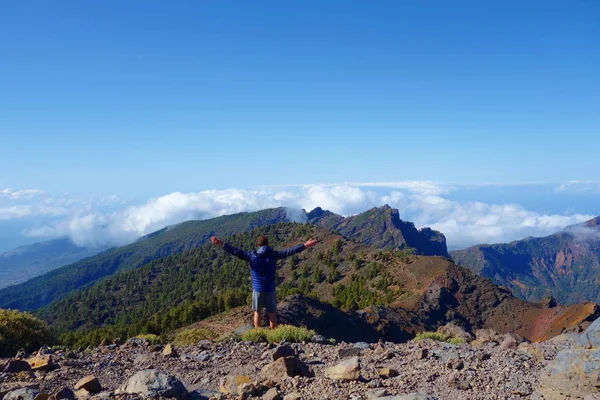 Young man above the sea of clouds on a hiking trail GR131, La Palma island