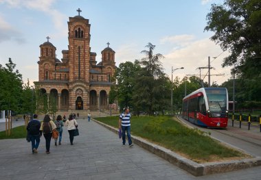 Belgrade, Sırbistan - 04 Mayıs 2018: Akşam görünümü St. Mark Kilisesi ve yeni kırmızı tramvay. Turistler ve yürüyen vatandaşlar.