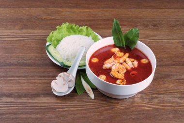 Tom yum veya tom yam genellikle pişmiş karides ile sıcak ve ekşi Tay çorba türüdür. Pirinç ve sebze ahşap kahverengi masa üzerinde