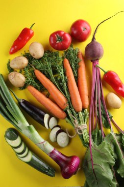 Taze sebzeler. Domates, kabak, patates, havuç, patlıcan, pancar ve biber parlak sarı arka planda. Flatlay, üst manzara. Arkaplan resmi, alanı kopyala 
