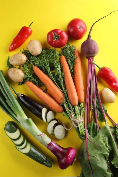 Taze sebzeler. Domates, kabak, patates, havuç, patlıcan, pancar ve biber parlak sarı arka planda. Flatlay, üst manzara. Arkaplan resmi, alanı kopyala 
