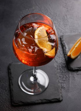 Alkolik içecekler. Kokteyl aperol şırıngası. Siyah arka planda turuncu ve buzlu bir bardakta kırmızı kokteyl. Dikey. Arkaplan resmi, alanı kopyala