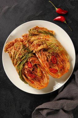 Kore ulusal mutfağı. Sebzeli Pekin lahana turşusu, kırmızı sos ve siyah arka planda beyaz tabakta kırmızı biber. Düztaban, dikey. Arkaplan resmi, alanı kopyala