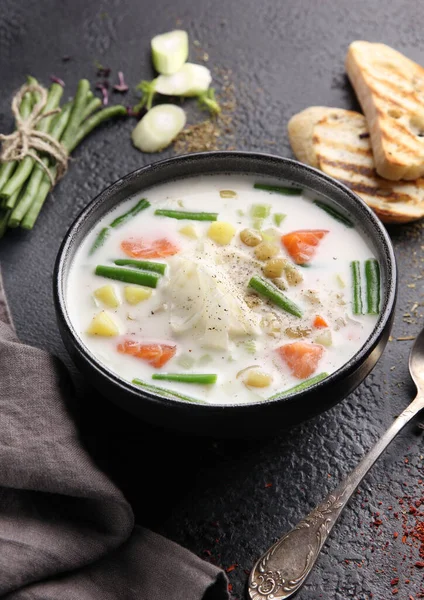 Somonlu kremalı çorba, kuşkonmaz fasulyesi, patates ve kızarmış ekmek siyah arka planda. Dikey. Arkaplan resmi, alanı kopyala