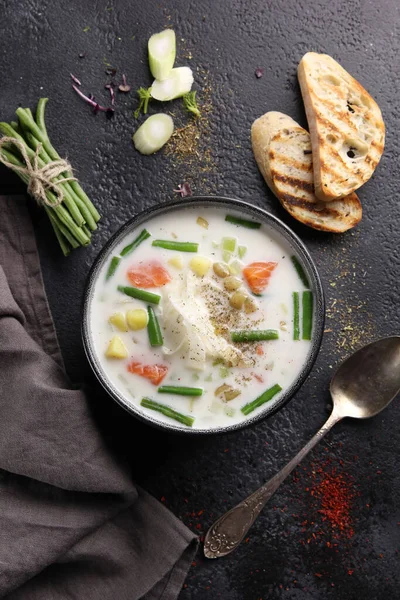 Somonlu kremalı çorba, kuşkonmaz fasulyesi, patates ve kızarmış ekmek siyah arka planda. Düztaban, dikey. Arkaplan resmi, alanı kopyala