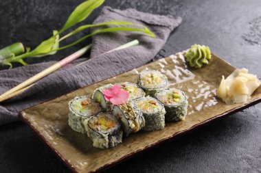 Japon mutfağı. Zencefil ve wasabi ile sıcak rulo sıcak yeşil bir tabak üzerinde yemek çubukları ile siyah bir masada. Restoran menüsü. Arkaplan resmi, alanı kopyala