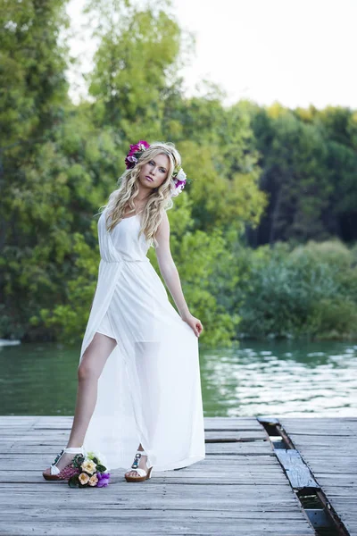 ぼやけて自然の背景と髪の長い若い金髪の女性 湖の横にある桟橋にロマンチックなポーズで立っている魅力的な花嫁 — ストック写真