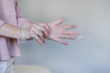Koronavirüs salgını sırasında tek kullanımlık güvenlik eldivenleri takan bir kadının elleri.