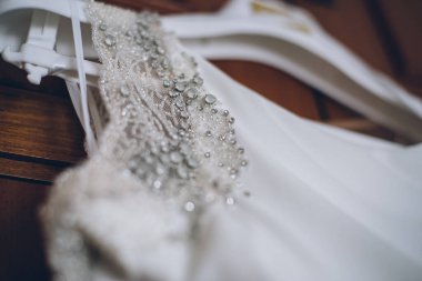 Askıda asılı bir gelinliğin el işi süslemesinin ayrıntıları.