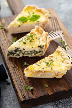 Bir servis tahtasıüzerinde üç quiche parçaları