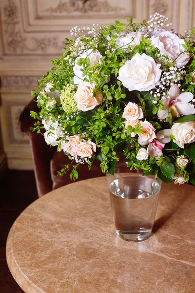 Bouquet of white roses on marble table in interior of the Baroque style