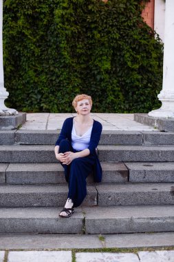 Rahat ve açık üzerinde gülümseyen mutlu oturma portre emin çekici orta yaşlı kadın parkta adımlar