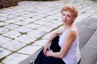 Rahat ve açık üzerinde gülümseyen mutlu oturma portre emin çekici orta yaşlı kadın parkta adımlar