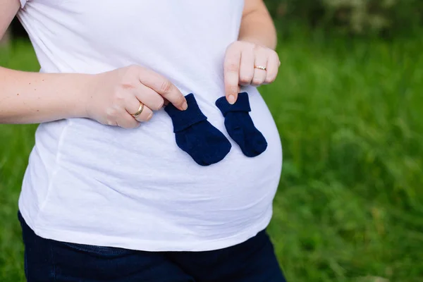 Беременная женщина держит в руках детские носки — стоковое фото