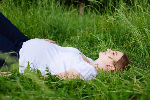 美丽的孕妇在公园的草地上放松 — 图库照片