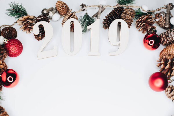 Christmas and New Year composition. 2019 simbols and fir branches with cones and christmas balls in red colours on white background. Flat lay, top view, copy space for text