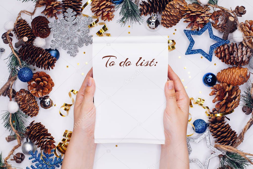 Woman hands with notepad on Christmas and New Year background. To do list or list of promises, place for your text