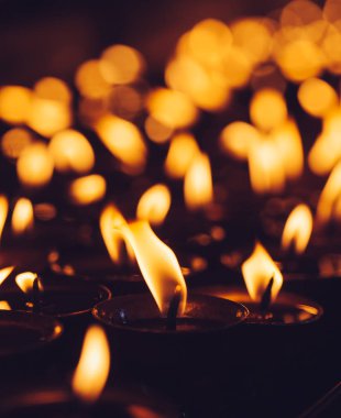 Many candle flames glowing in the dark with shallow depth of field clipart