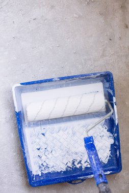 Beyaz boya ve fırça rulo boya tepsi ile mavi kova