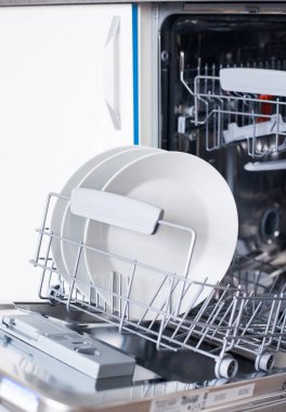 Bulaşık makinesini beyaz mutfakta temiz bulaşıklarla açın.