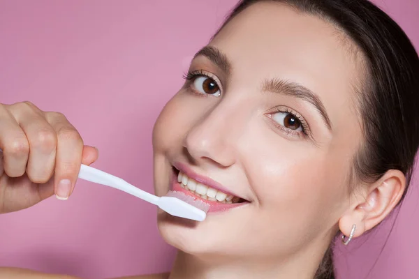 Όμορφη νεαρή γυναίκα χαμογελά με οδοντόβουρτσα — Φωτογραφία Αρχείου