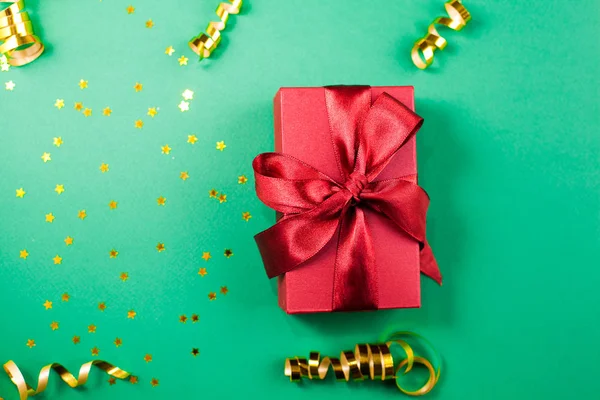 Caja de regalo y decoraciones de oro y destellos en ba verde brillante —  Fotos de Stock