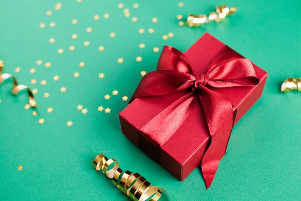 Подарочная коробка и золотые украшения и блески на ярко-зеленой ба — стоковое фото