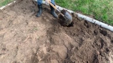 Çiftçi kauçuk çizmeler kazma ve kürek kullanarak toprak çevirme ve bir weed çekerek. Tarım, toprak işleme konsepti