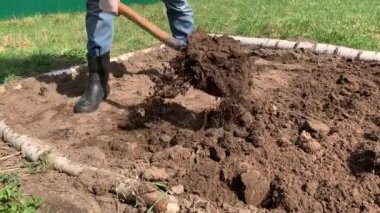 Çiftçi kauçuk çizmeler kazma ve kürek kullanarak toprak çevirme ve bir weed çekerek. Tarım, toprak işleme konsepti