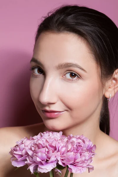 Jovem mulher bonita com flor no fundo rosa . — Fotografia de Stock