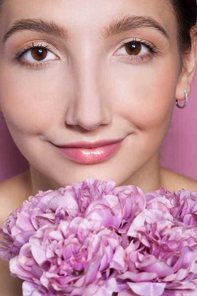 Jeune belle femme avec des fleurs sur fond rose . — Photo