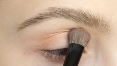 Makyaj fırçası kullanarak göz farı uygulayan kadının yakın çekim portresi