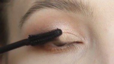 Fırça kullanarak maskara uygulayan kadının yakın çekim portresi