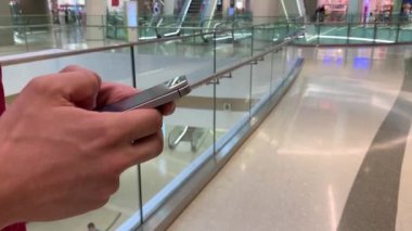Alışveriş merkezinde akıllı telefon kullanan genç adamın elleri. İletişim, online alışveriş, sohbet, sosyal ağ konsepti