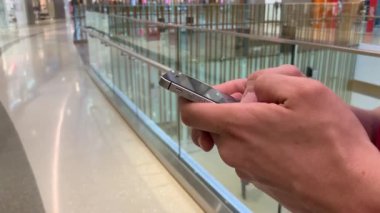 Alışveriş merkezinde akıllı telefon kullanan genç adamın elleri. İletişim, online alışveriş, sohbet, sosyal ağ konsepti