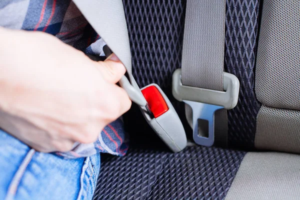 Erkek eli arabanın emniyet kemerini bağlar..