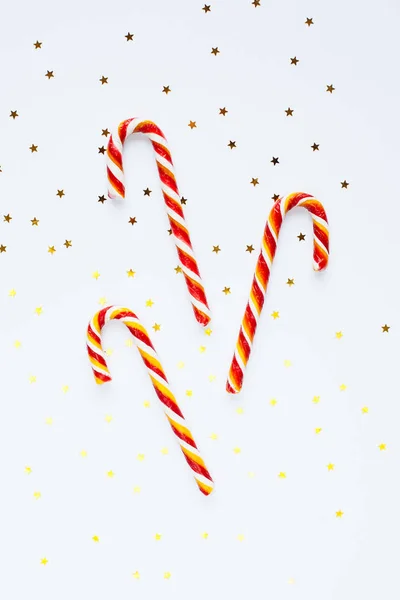 Composición navideña. Bastones de caramelo con confeti de oro sobre blanco —  Fotos de Stock