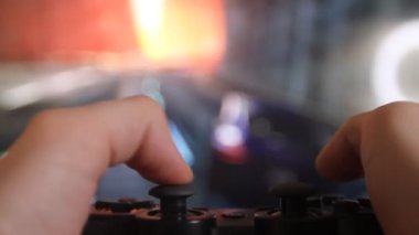 Geniş ekran TV 'nin önündeki oyun konsolunda oyun oynayan adamın ellerine yakın çekim