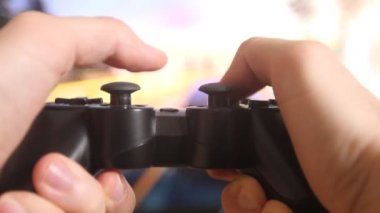 Geniş ekran TV 'nin önündeki oyun konsolunda oyun oynayan adamın ellerine yakın çekim