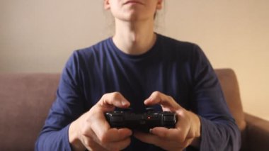 Kanepede oturmuş oyun konsolunda video oyunu oynayan adamın elleri yakın plan.