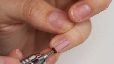 Kadın beyaz arka planda tek başına manikür yapıyor. Kendi kendine yapılan manikür hizmeti