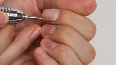 Kadın beyaz arka planda tek başına manikür yapıyor. Kendi kendine yapılan manikür hizmeti