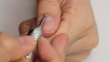 Kadın beyaz arka planda tek başına manikür yapıyor. Kendi kendine yapılan manikür hizmeti