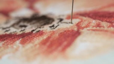 Kadın elleri kırmızı çiçeğe çapraz dikiş atıyor. Kapalı bir nakış..