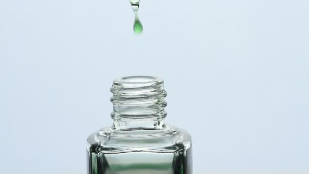 緑の油滴の閉じ込めは 白い背景に ピペットから落下します ボトルに油を滴下ドロッパー 美容とヘルスケア マクロショット — ストック動画