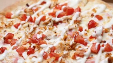 Peynirli, sebzeli ve soslu sıcak sulu pizza masanın üzerinde döner. Makro çekim.