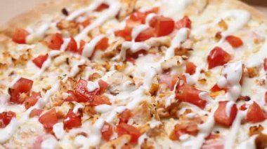 Peynirli, sebzeli ve soslu sıcak sulu pizza masanın üzerinde döner. Makro çekim.