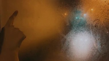 Kadın parmağını kapat ve ıslak pencereye sokak lambasına aşk kelimesi yaz.