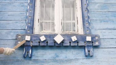 İşçi yenileme için eski ahşap bir yüzey öğütüyor. Eski evin restorasyonu. Kafkas erkek el fırçasıyla duvara sürtünüyor. İş eldiveni giyiyor.. 