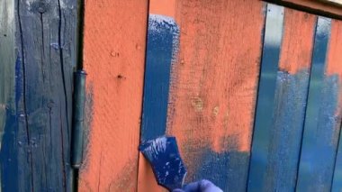 Ahşap. Mavi kauçuk eldiven, ahşap tahtayı fırçayla kaplıyor. Ev atölyesi, el işi, el yapımı konsept. Kamera perspektifinden çekilmiş. POV